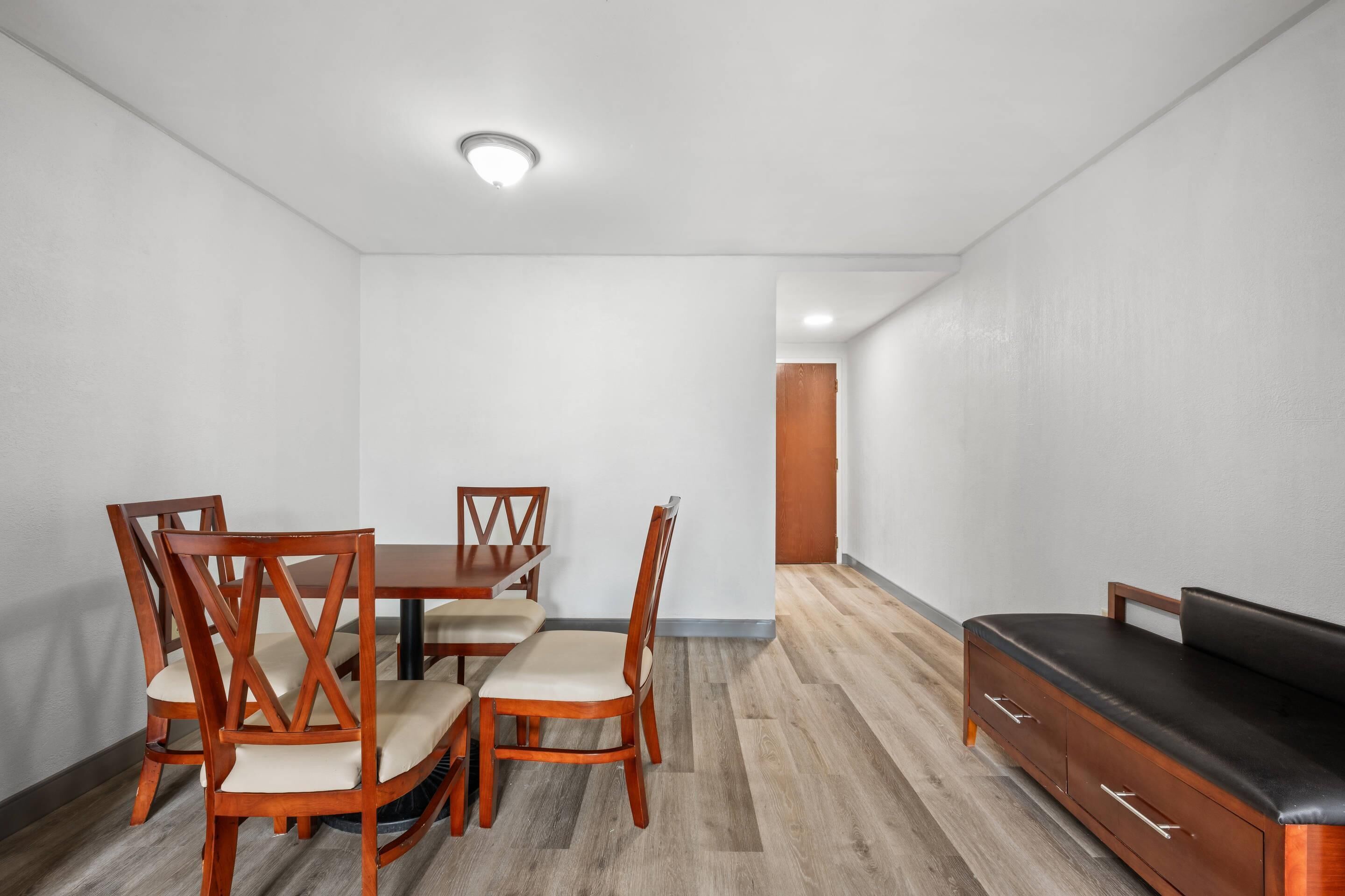A dining area with wooden chairs and a table, a sofa, and a wooden cabinet.