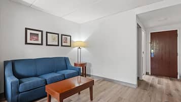 Un salon avec un canapé bleu, une table basse en bois et un lampadaire. Deux tableaux encadrés sont accrochés au mur.