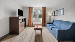 A modern living room with a blue sofa, a wooden coffee table, a flat-screen TV, and a built-in air conditioning unit.