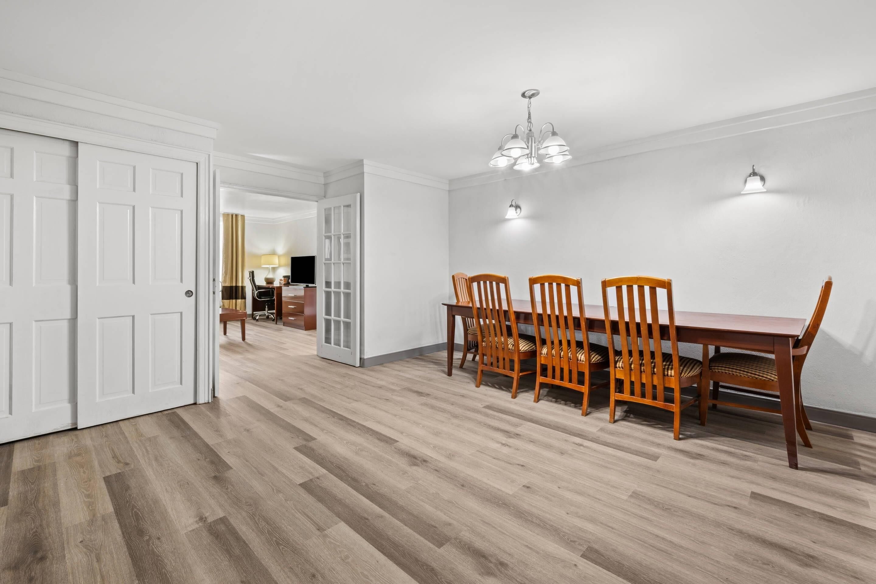 Comedor con mesa y sillas de madera, paredes blancas y piso de madera clara.