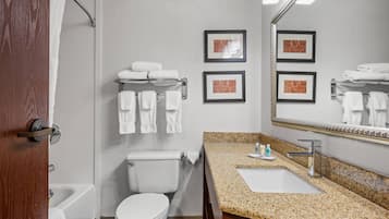 A bathroom with a toilet, sink, and bathtub. There are towels on a rack and framed pictures on the wall.