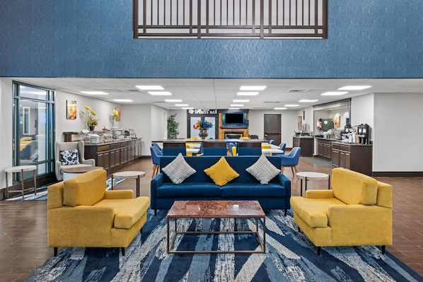 A modern lobby with a blue sofa set, yellow armchairs, a coffee bar, and a sports bar.