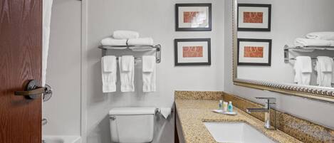 A bathroom with a toilet, sink, and bathtub. There are towels on a rack and framed pictures on the wall.