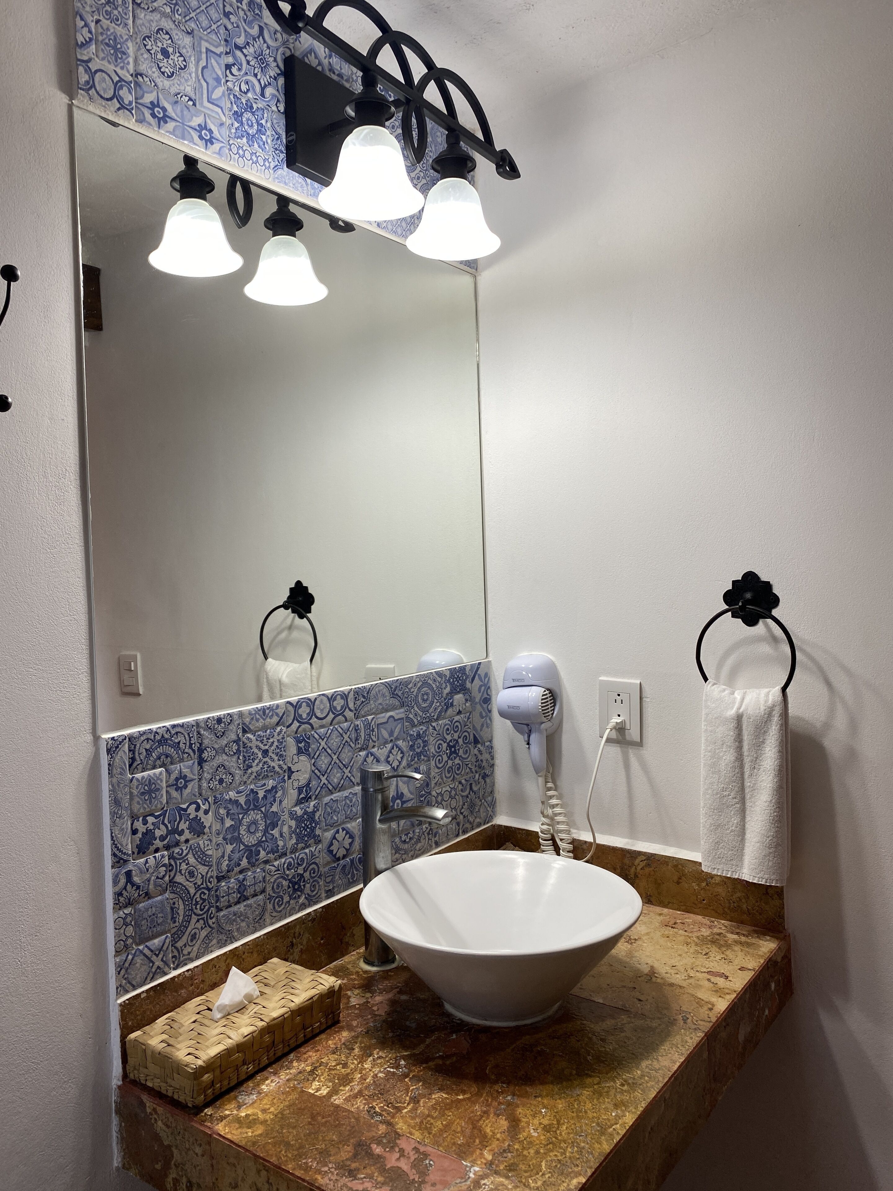 A bathroom with a white sink, a large mirror, and a towel rack.