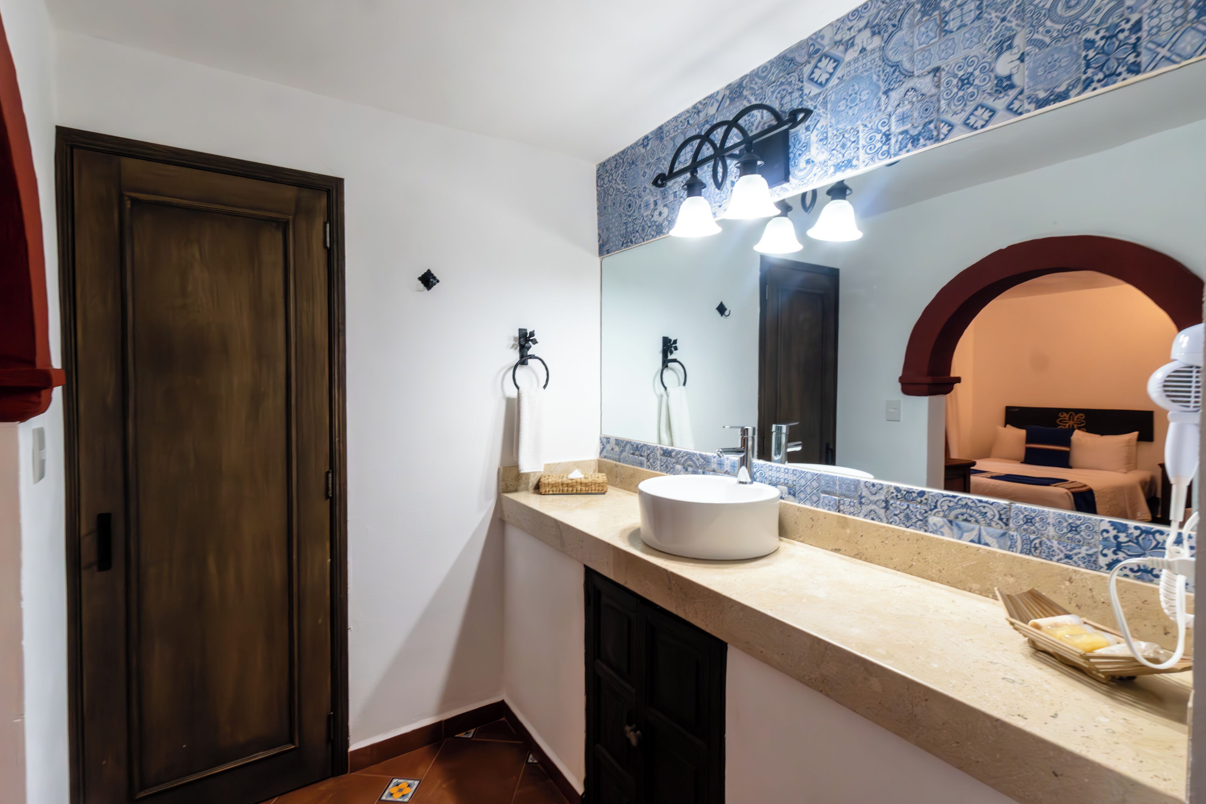 Un baño con un espejo grande, un lavabo y un perchero para toallas.