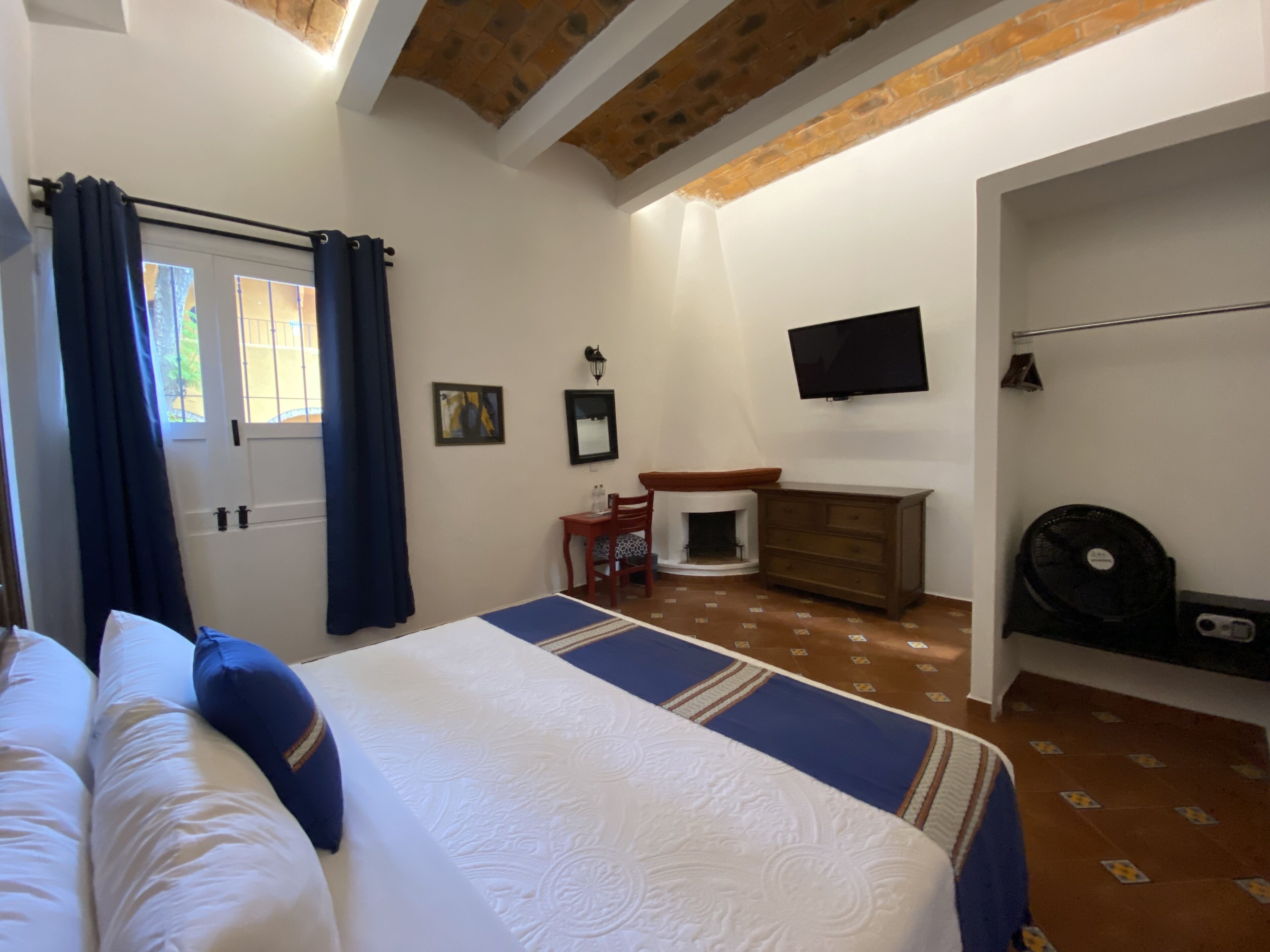 Un dormitorio con cama, cómoda, televisión y chimenea.