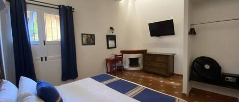 A bedroom with a bed, a dresser, a television, and a fireplace.