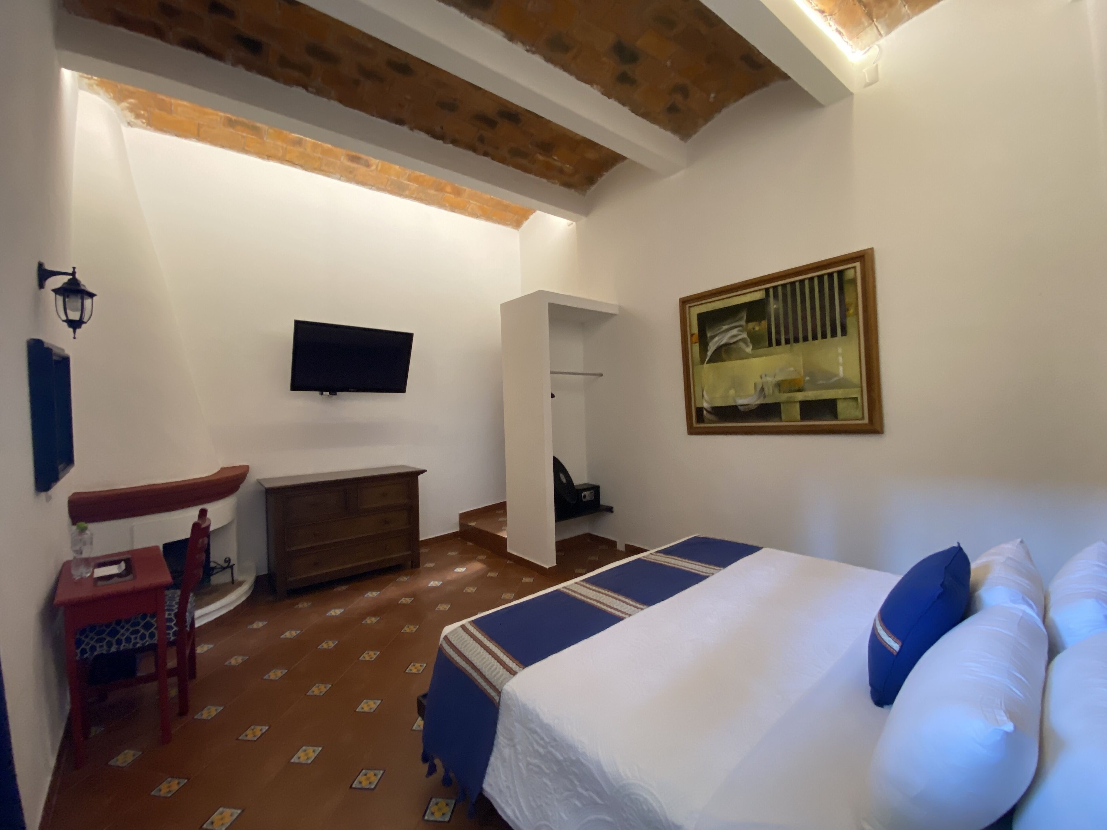 A bedroom with a bed, a dresser, a TV, a chair, and a mirror.