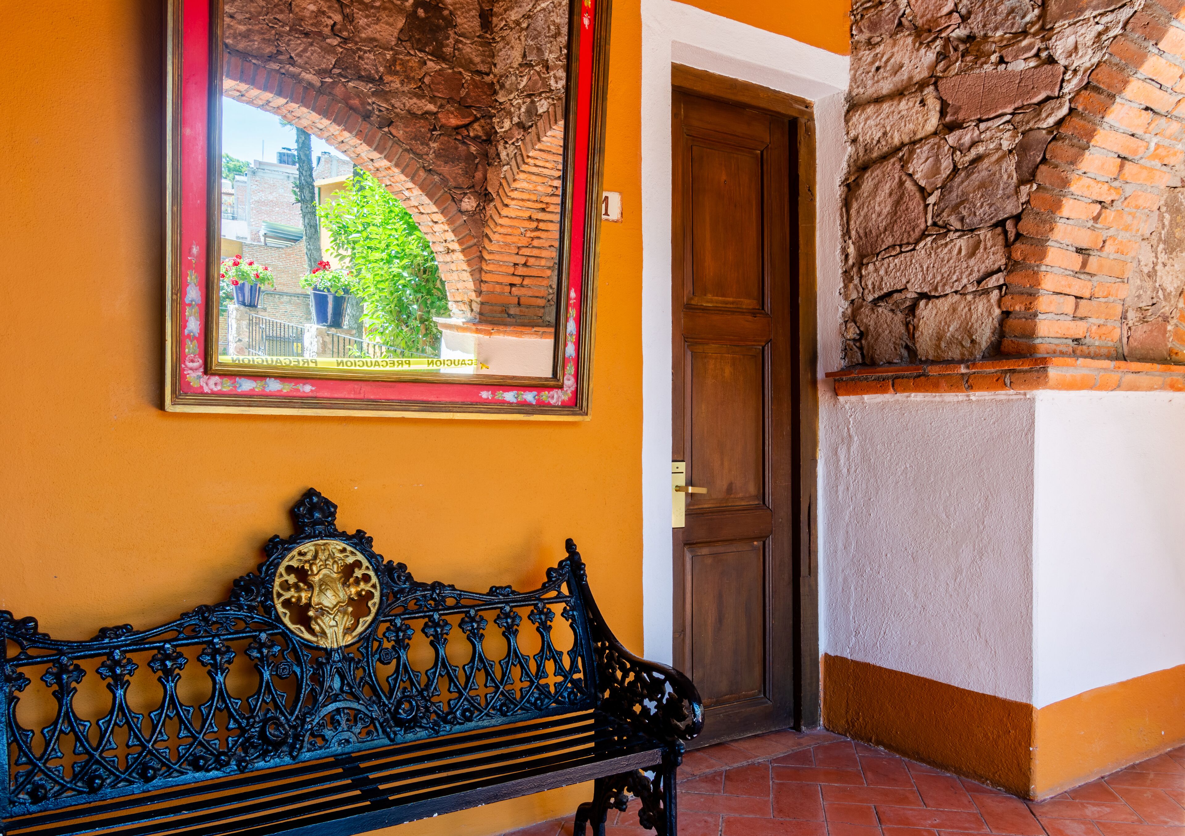 A bench with a decorative backrest, a door, and a brick wall.