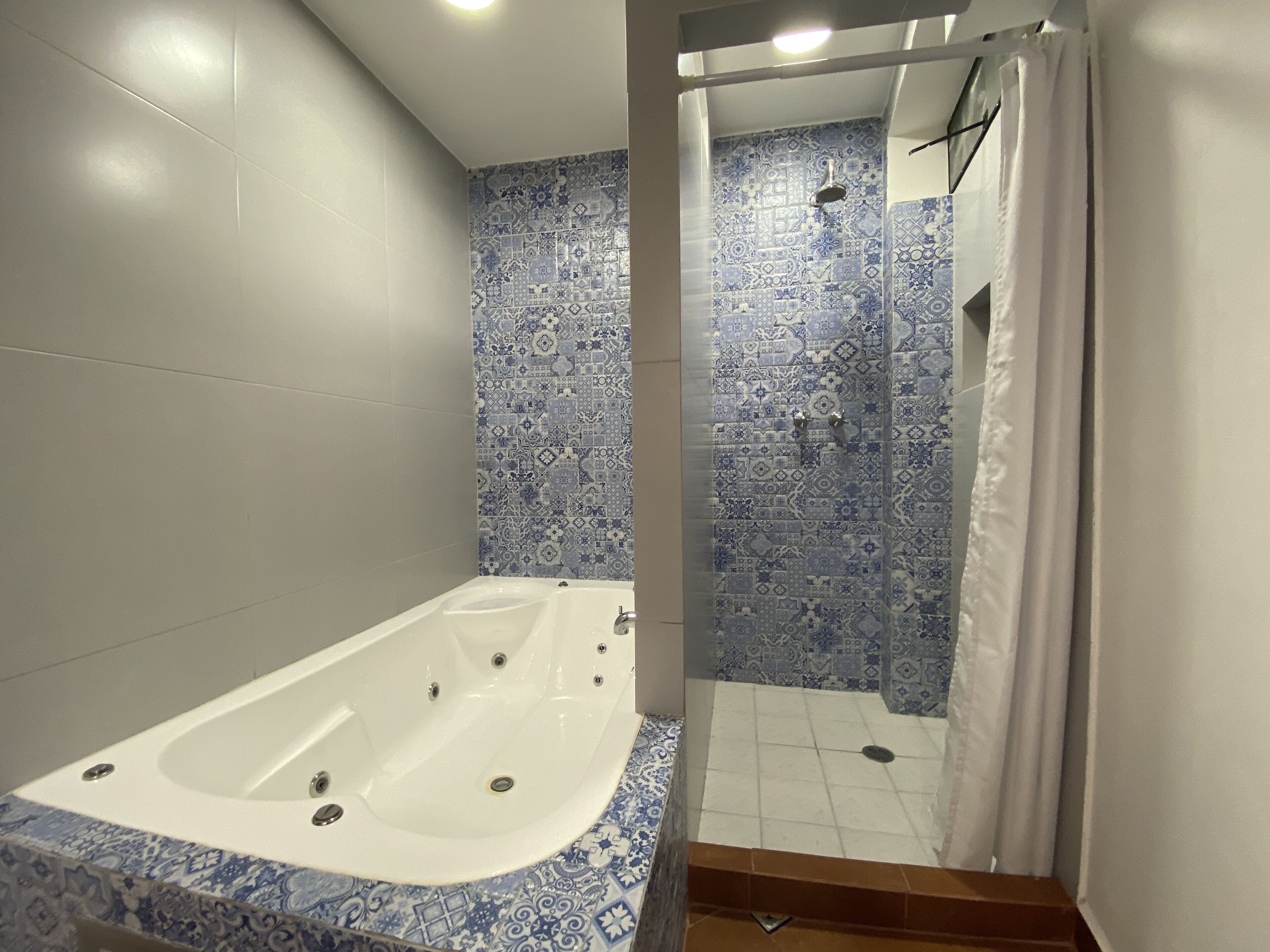 Une salle de bain avec une baignoire, une douche et des murs carrelés.
