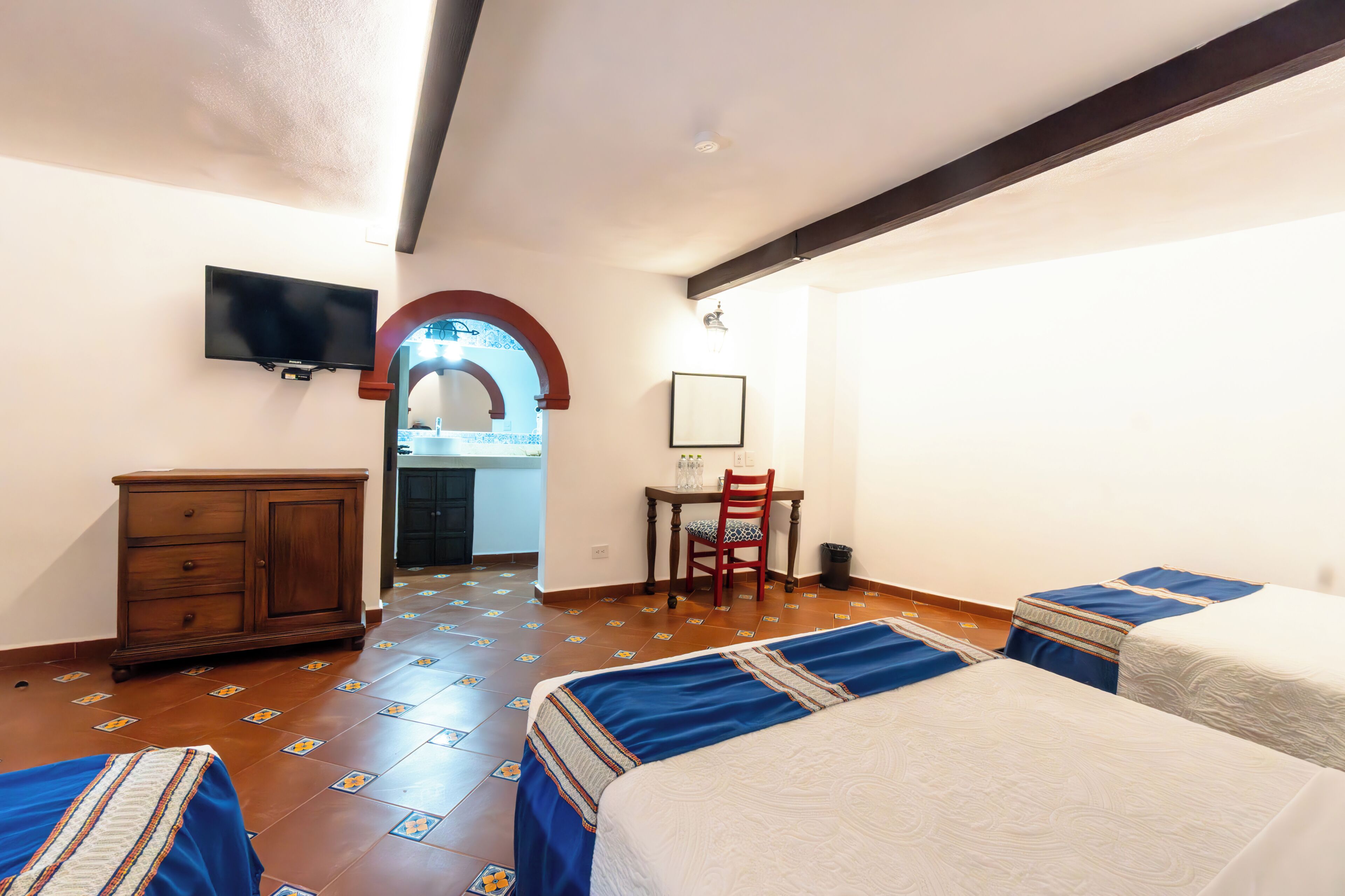 Habitación de hotel con dos camas, un escritorio, una silla, un televisor y un armario.