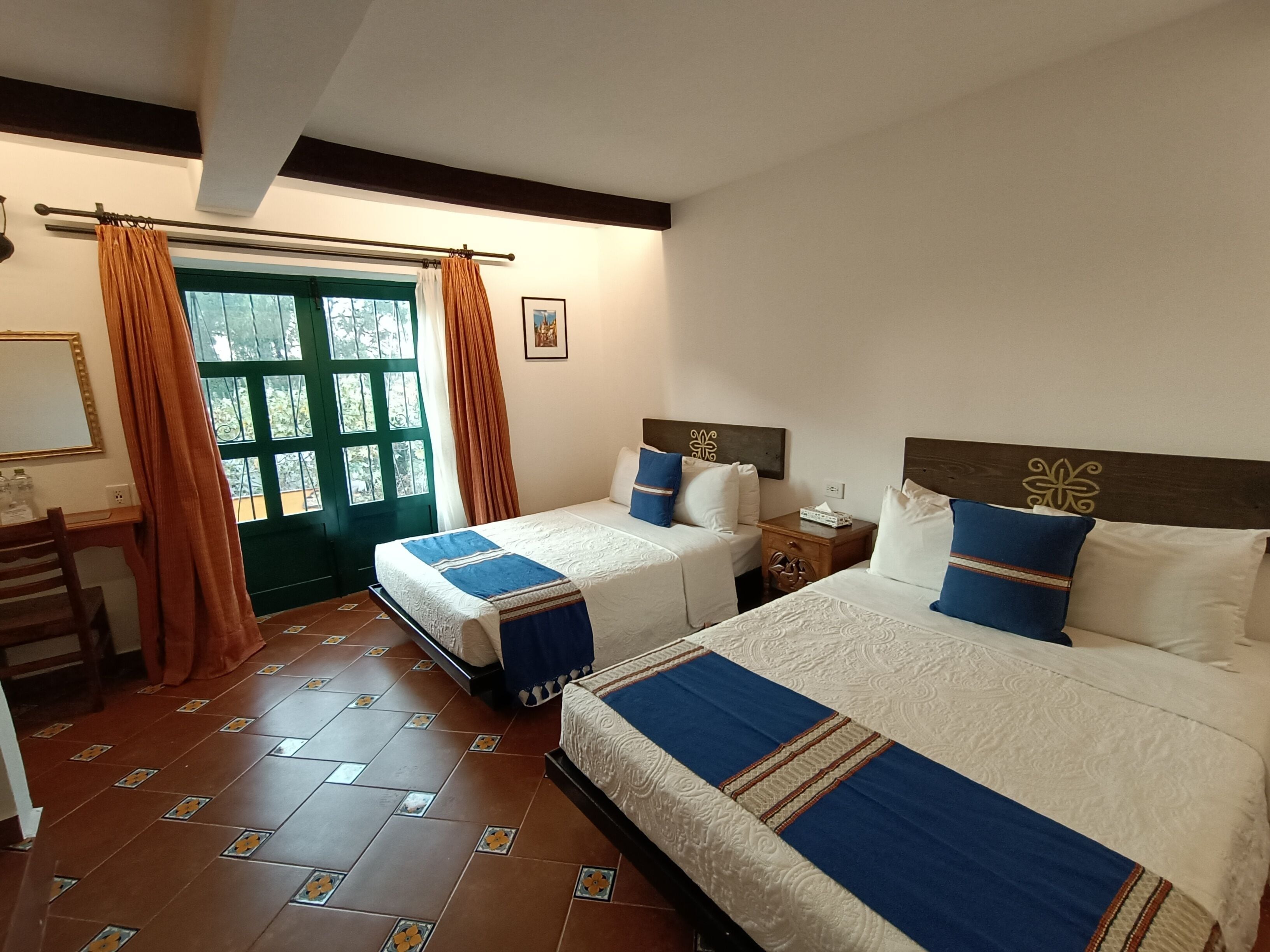 Una habitación de hotel con dos camas, un escritorio y una ventana con cortinas.