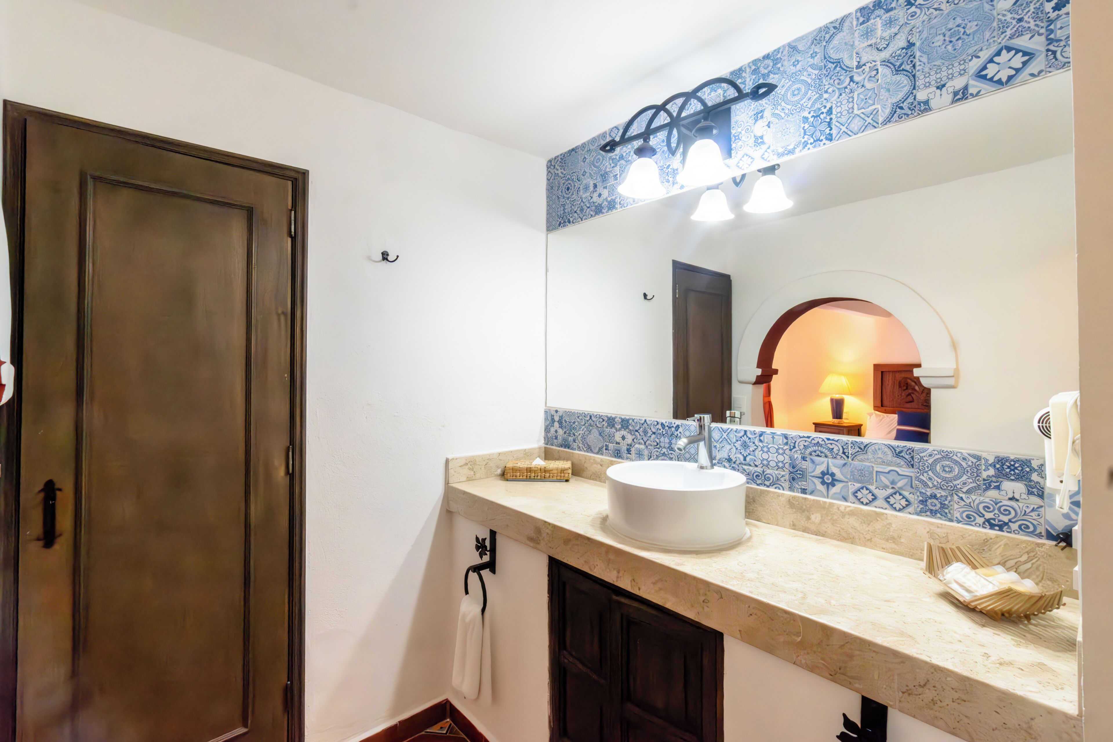 A bathroom with a large mirror, a sink, and a towel rack.