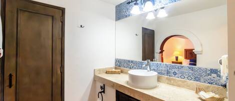A bathroom with a large mirror, a sink, and a towel rack.