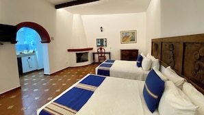 Une chambre d’hôtel avec deux lits, une cheminée, un bureau et une vue sur la cuisine.