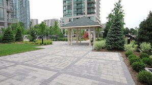 A spacious outdoor area with a gazebo, surrounded by greenery and modern buildings. - Maplewood Furnished Suites (Mississauga)