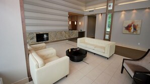 A modern living room with a white sofa, a black coffee table, and a flat-screen TV mounted on a stone wall. - Maplewood Furnished Suites (Mississauga)