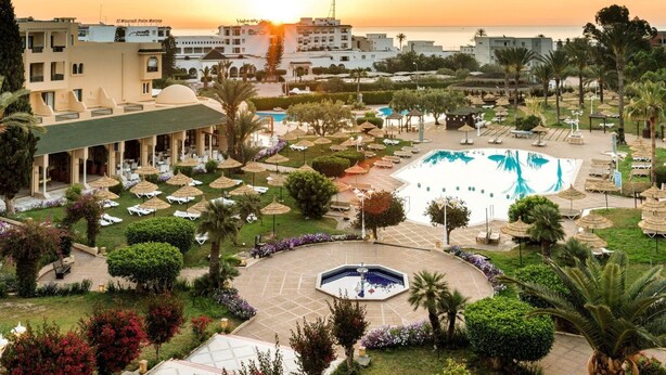 A resort with a swimming pool, lounge areas, and a view of the sunset over the sea. - TUI SUNEO Royal Kenz (Port El Kantaoui)