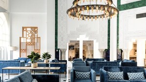 A spacious lobby with blue sofas, a marble coffee table, and a decorative chandelier. - TUI SUNEO Royal Kenz (Port El Kantaoui)