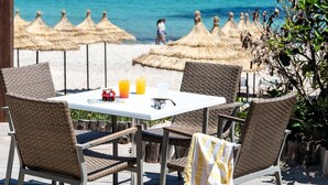 A table with wicker chairs and a white tablecloth, overlooking a beach with thatched umbrellas and the ocean. - TUI SUNEO Royal Kenz (Port El Kantaoui)