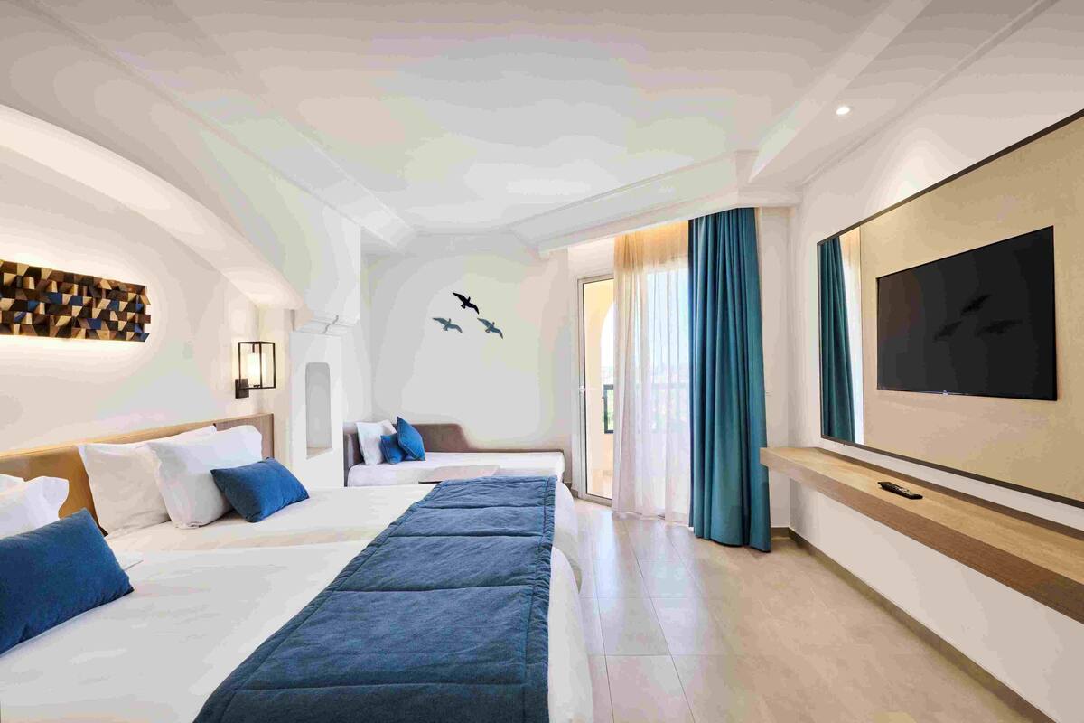A modern hotel room with a large bed, a TV, and a wall-mounted artwork.
