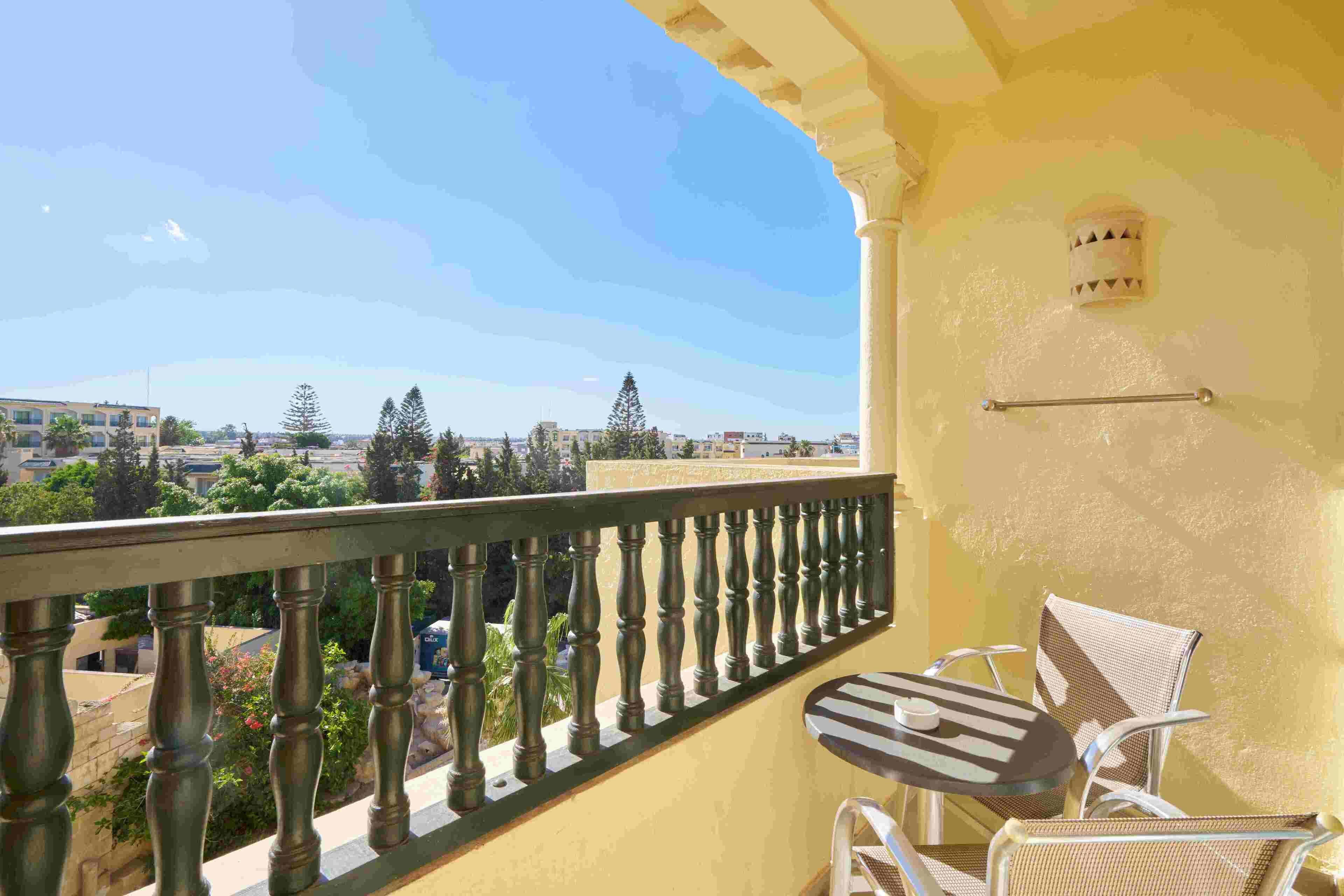 Uma varanda com vista para a cidade, uma mesa com cadeiras e um corrimão.