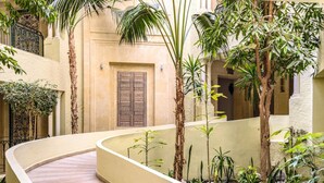 A curved pathway in a courtyard with palm trees and a decorative door. - TUI SUNEO Royal Kenz (Port El Kantaoui)