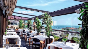 Ein Restaurant mit Außenbereich, Tischen, Stühlen und Kübelpflanzen.