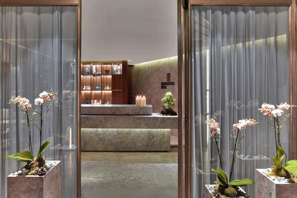 Una zona de recepción con mostrador de piedra, orquídeas en macetas y un letrero que dice "HOTEL SPA".