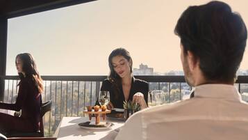 A dining area with a table set for three people, a city view, and a balcony railing.