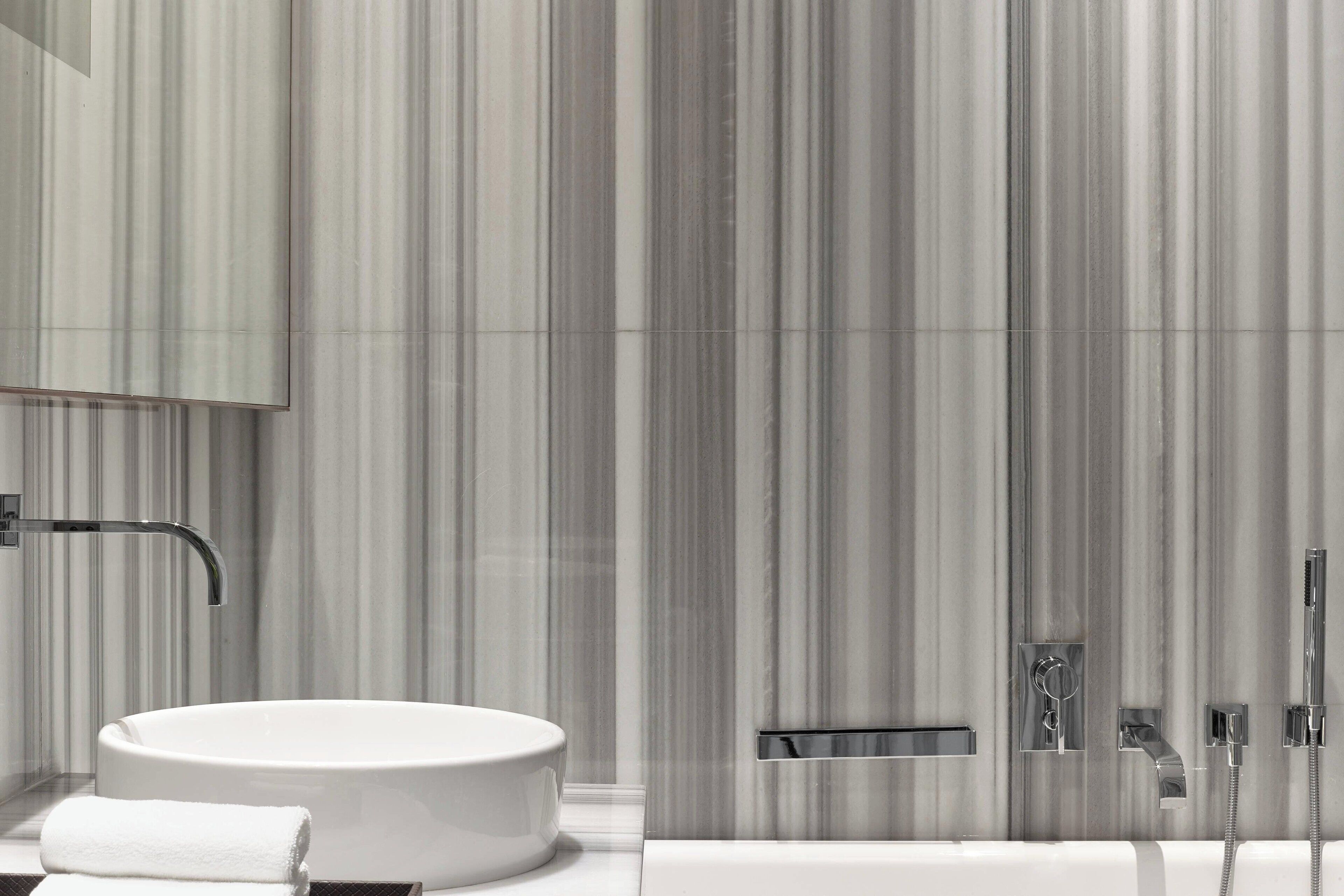 Une salle de bain moderne avec un lavabo rond, un miroir, une douche et des toilettes.