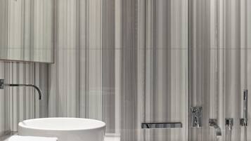 Une salle de bain moderne avec un lavabo rond, un miroir, une douche et des toilettes.