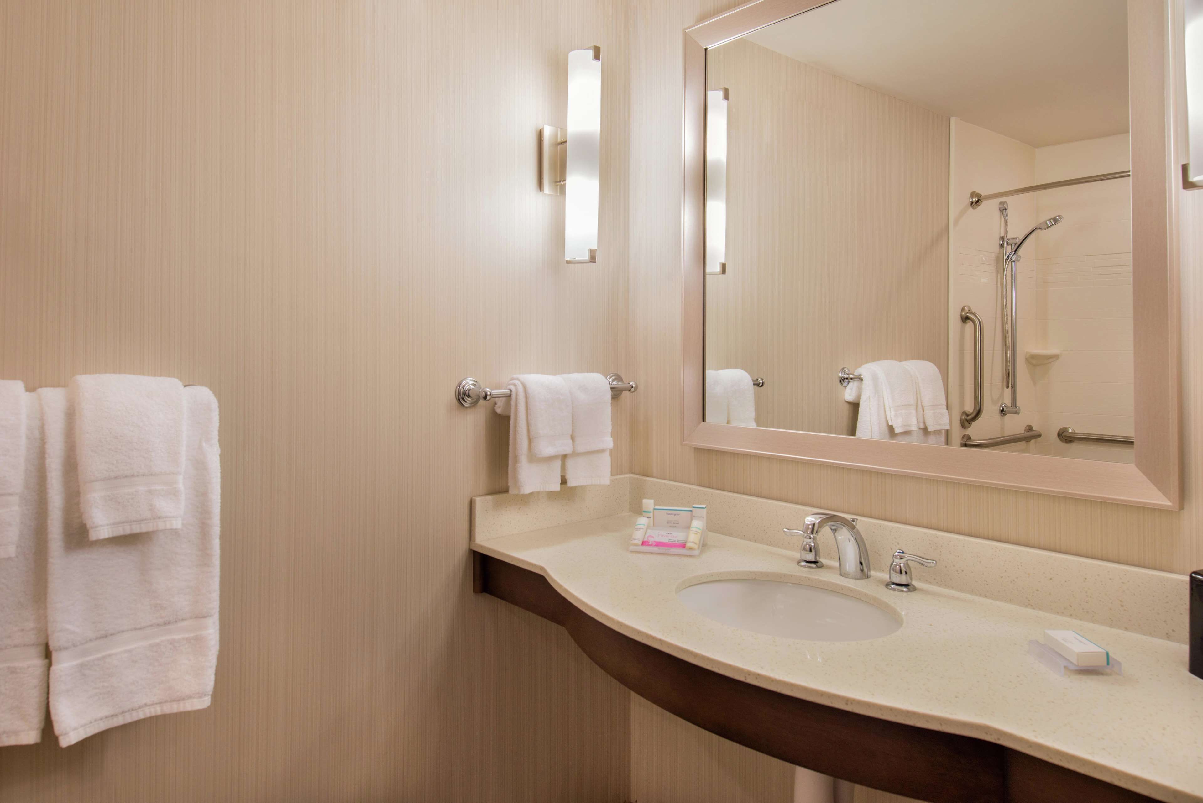 A bathroom with a sink, mirror, towel rack, and shower.