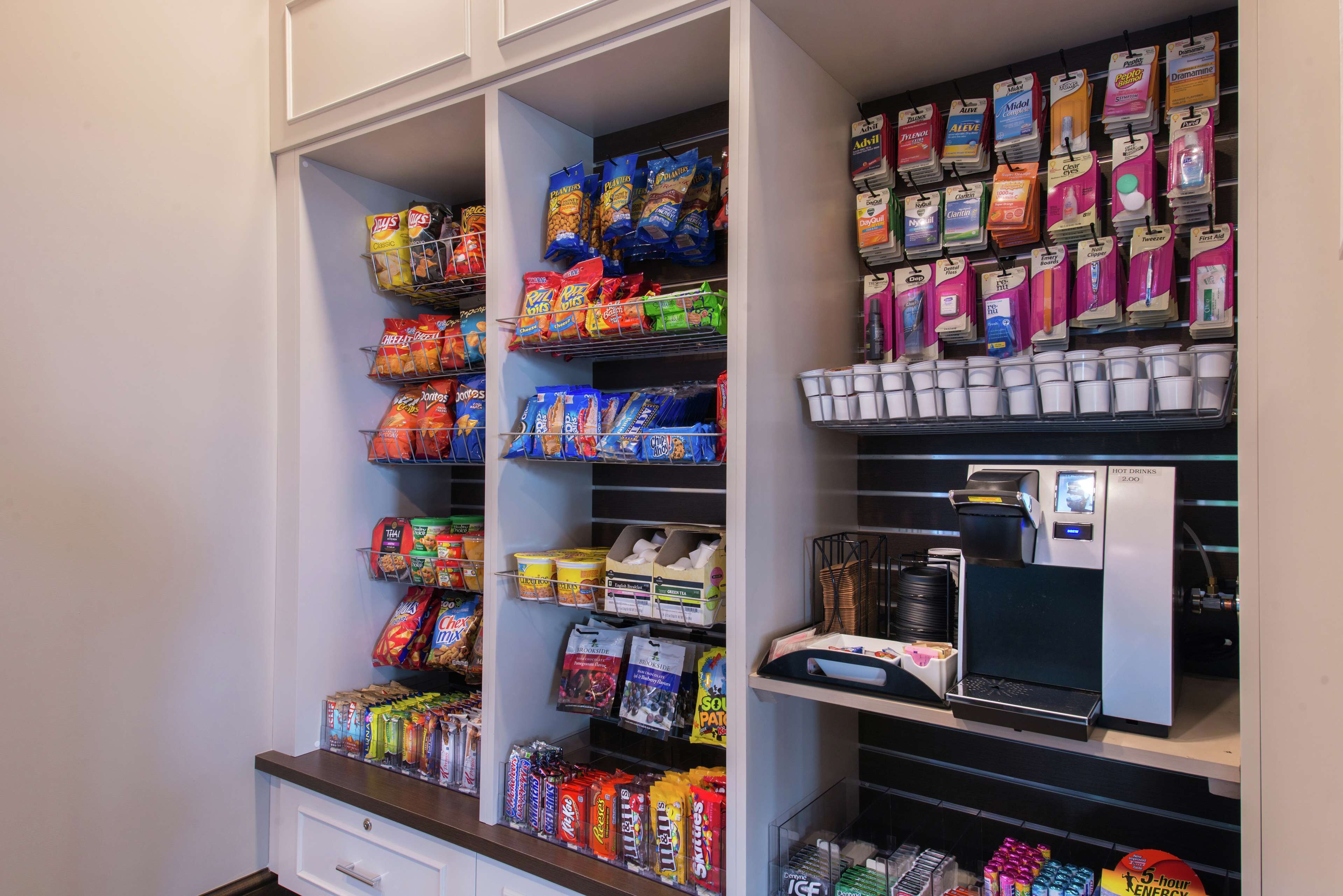 Una despensa bien organizada con diversas opciones de bocadillos, bebidas y una máquina de café.