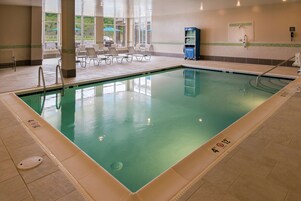 Una piscina interior con agua cristalina, suelo de baldosas y tumbonas.