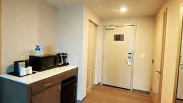 Habitación de hotel con kitchenette, piso de madera y puerta con cerradura.