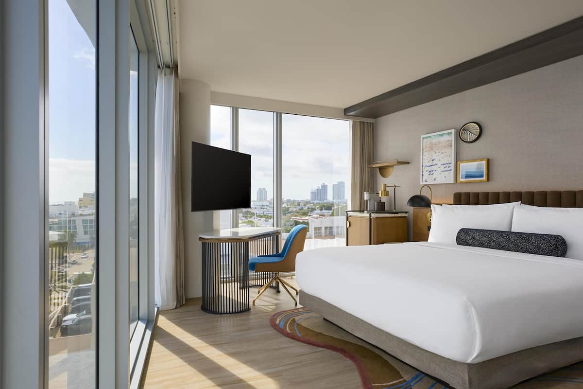 Una habitación de hotel moderna con una cama grande, un escritorio y un televisor.