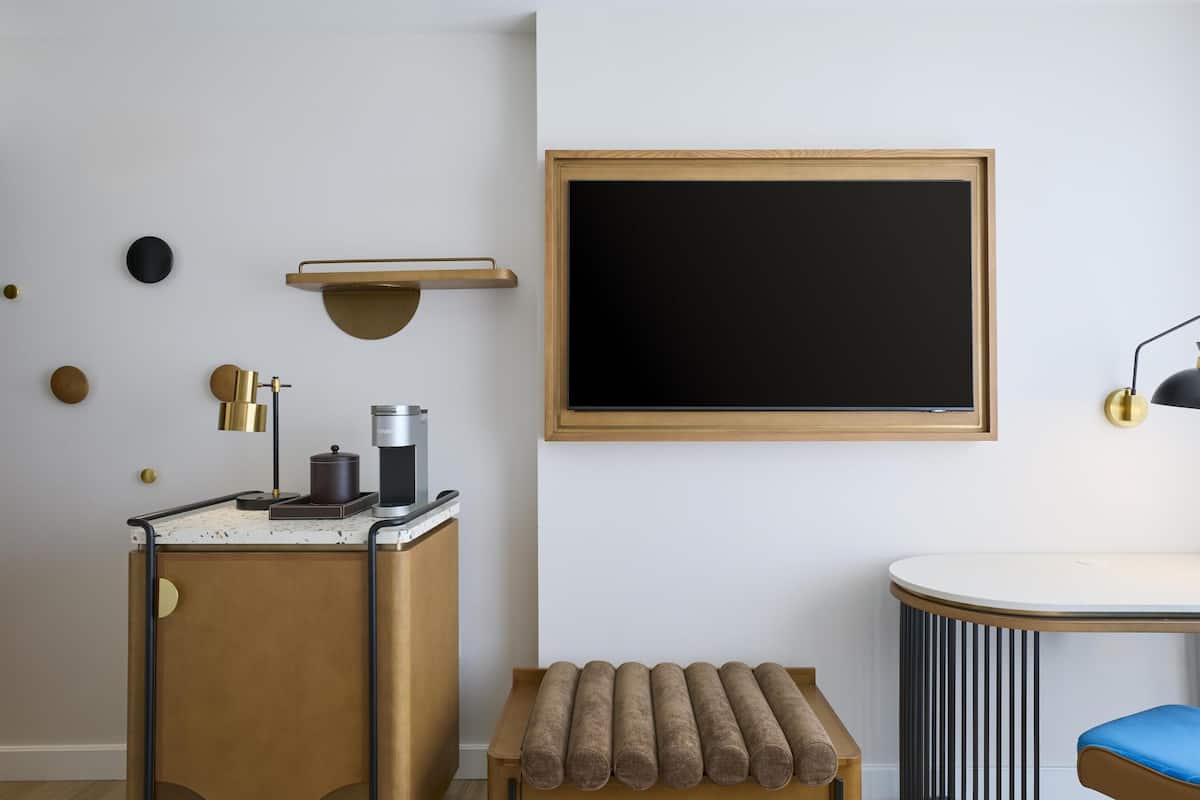 Una habitación moderna con cafetera, una mesa redonda, un banco y una pizarra en la pared.