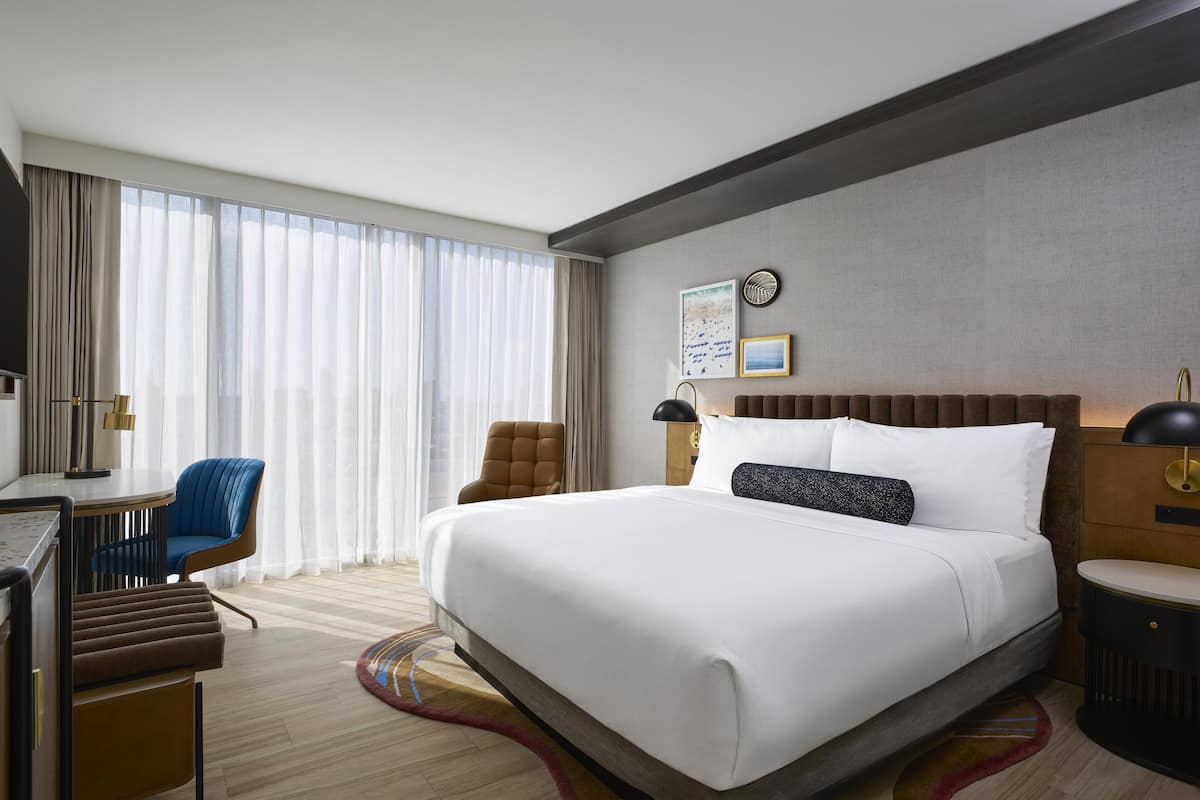 Una habitación de hotel con una cama grande, un escritorio, una silla y un televisor.