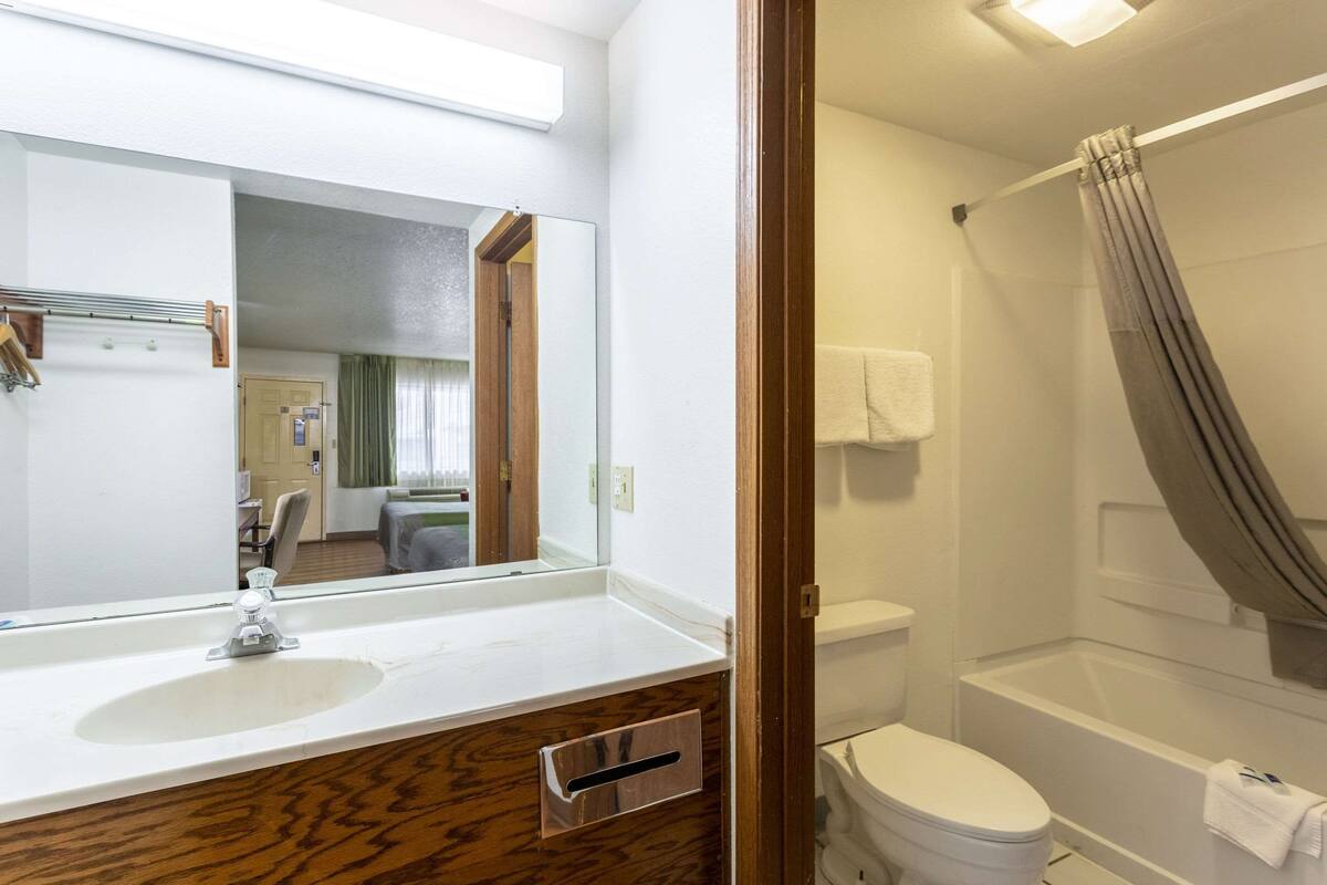A bathroom with a sink, mirror, toilet, and shower.