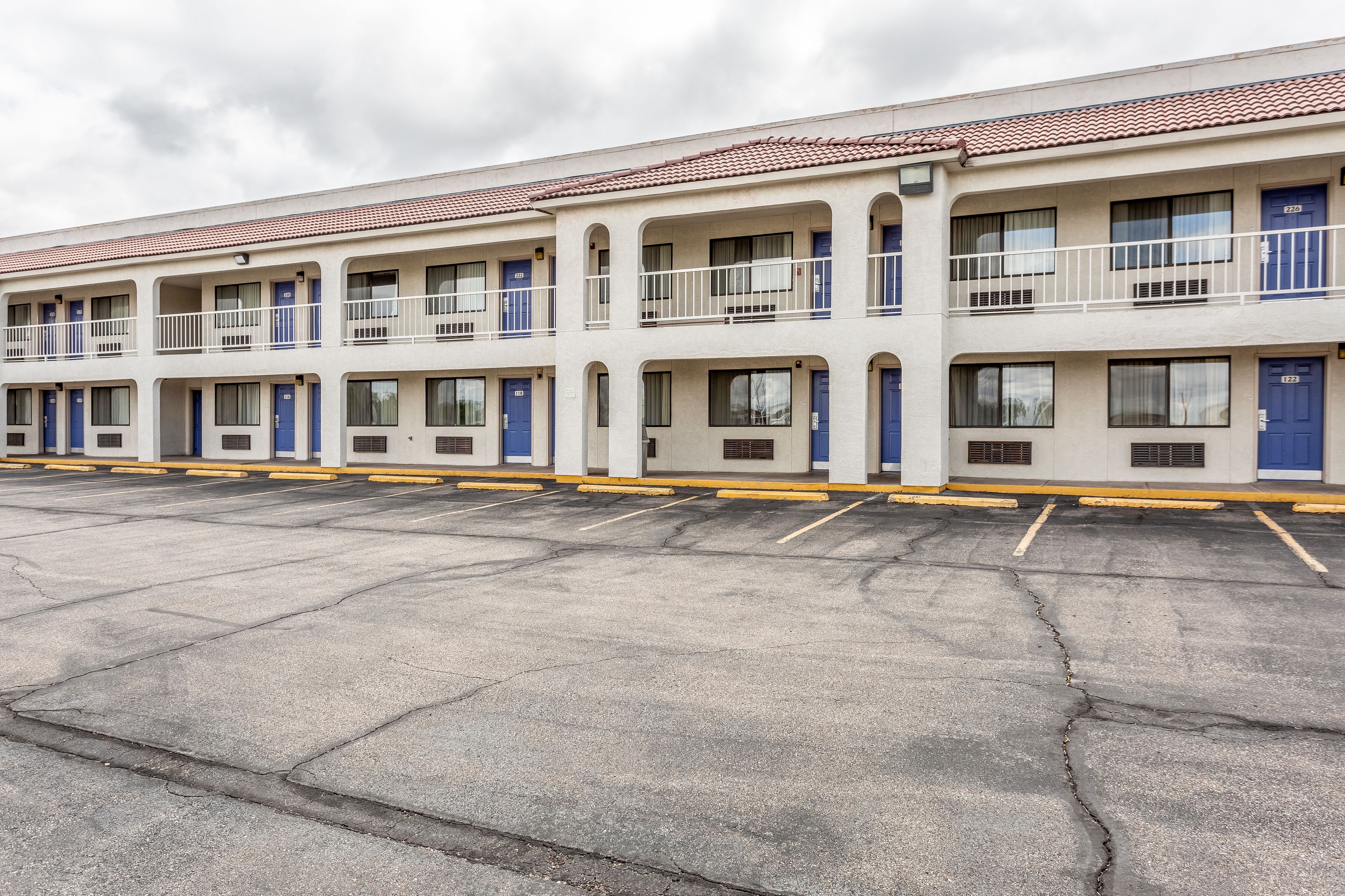 A row of motel buildings with multiple floors, each featuring balconies and a uniform exterior design.