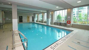 An indoor swimming pool with clear water, tiled floor, and a lifebuoy by the poolside. - Maplewood Suites - Square One (Mississauga)
