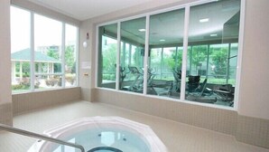 A spa area with a hot tub, large windows, and exercise equipment visible outside. - Maplewood Suites - Square One (Mississauga)