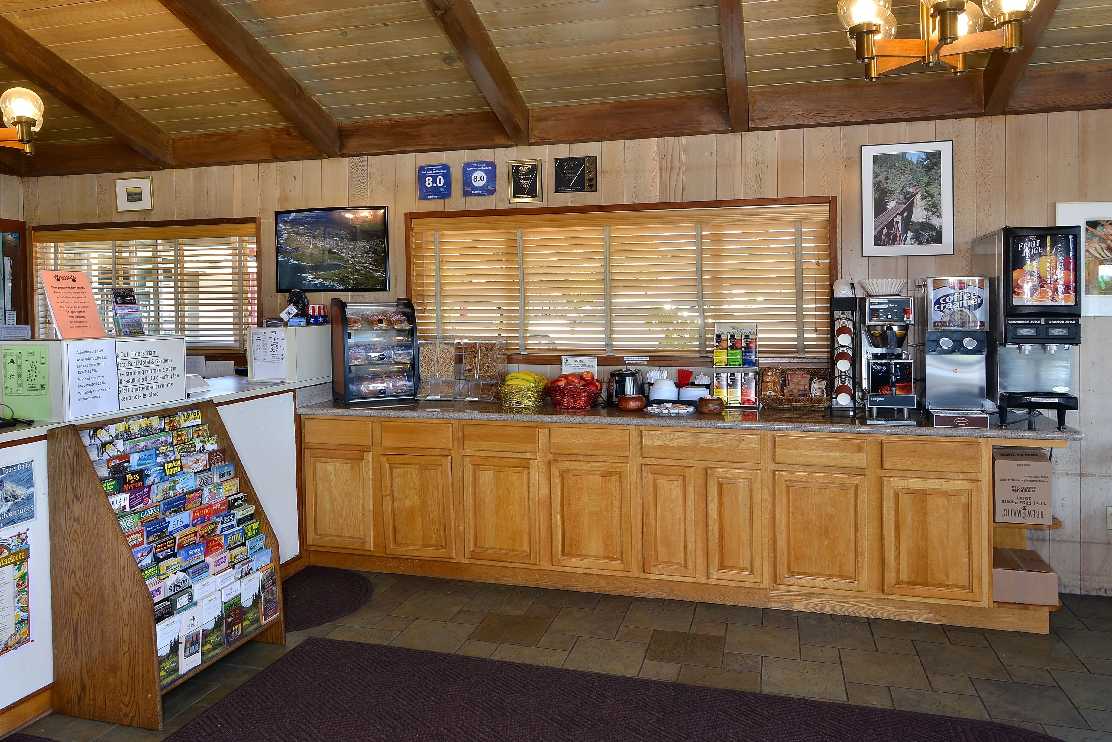 A wooden counter with coffee machines, a TV, and a window with blinds.