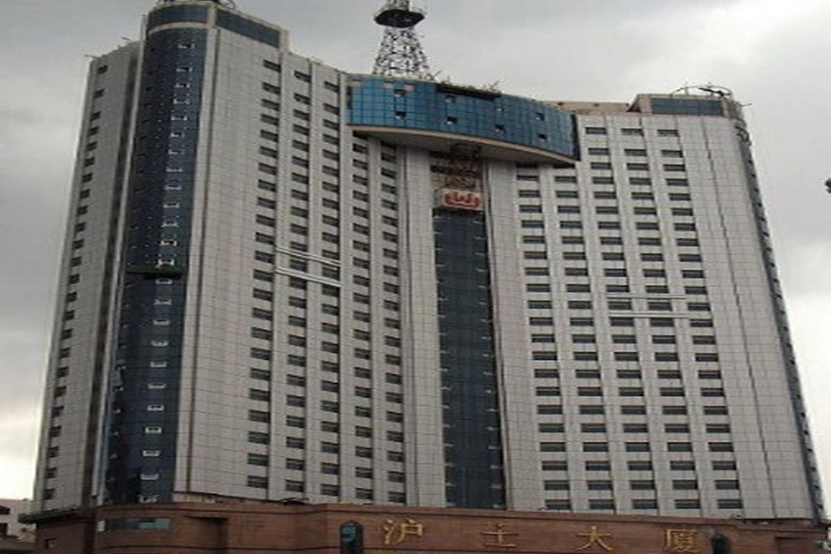 A high-rise building with multiple floors, a prominent antenna on top, and a sign with Chinese characters.