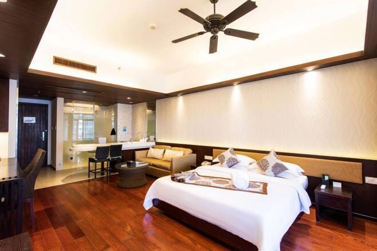 A modern hotel room with a large bed, a desk, and a seating area.