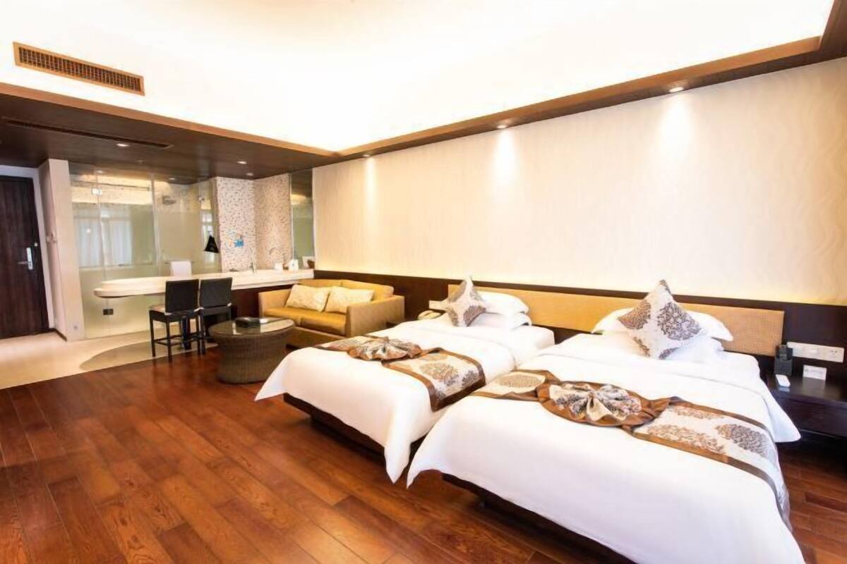 A modern hotel room with a large bed, a sofa, a desk, and a mirror.