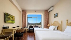 Une chambre d’hôtel équipée d’un lit, d’un bureau, d’une chaise et offrant une vue sur la ville grâce à une grande fenêtre.