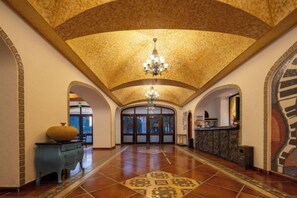 A spacious lobby with a high ceiling, a chandelier, and a patterned floor.