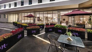 A hotel exterior with outdoor seating, potted plants, and a visible entrance. - Mercure Qingdao Downtown (Qingdao)
